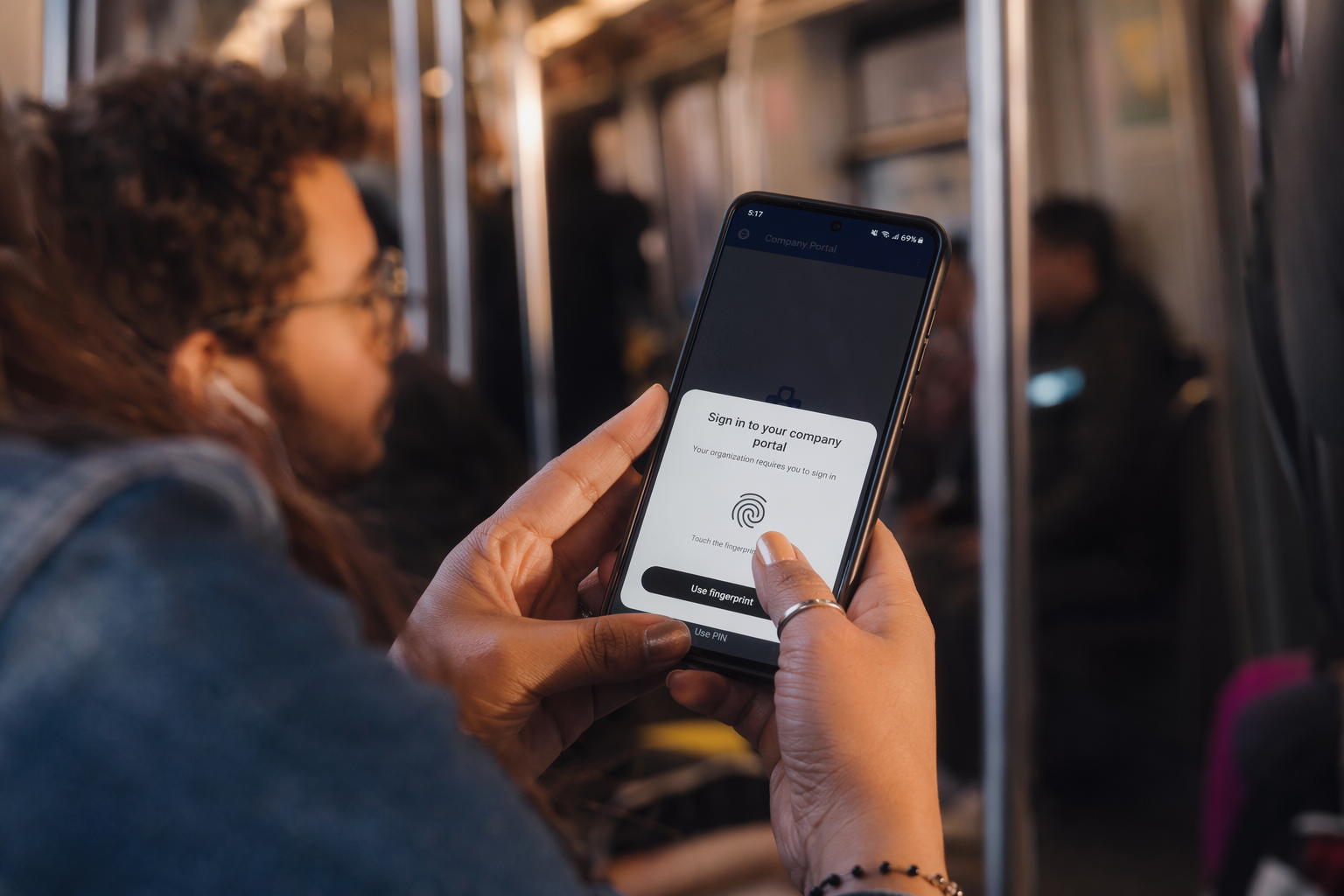 يدان تمسكان هاتف Android يعرض ورقة تأكيد مفتاح مرور ببصمة الإصبع للدخول إلى بوّابة الشركة أثناء التنقّل